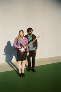a man and a woman standing next to a wall with a guitar